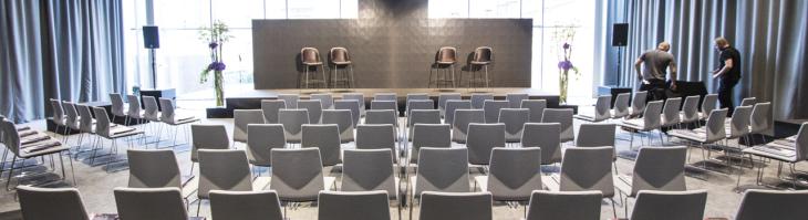 A conference hall with a stage and rows of chairs