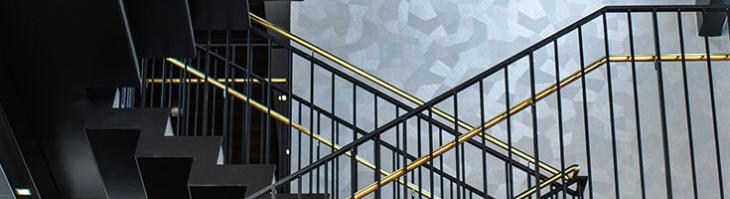 A stairwell with black steps and gold railings